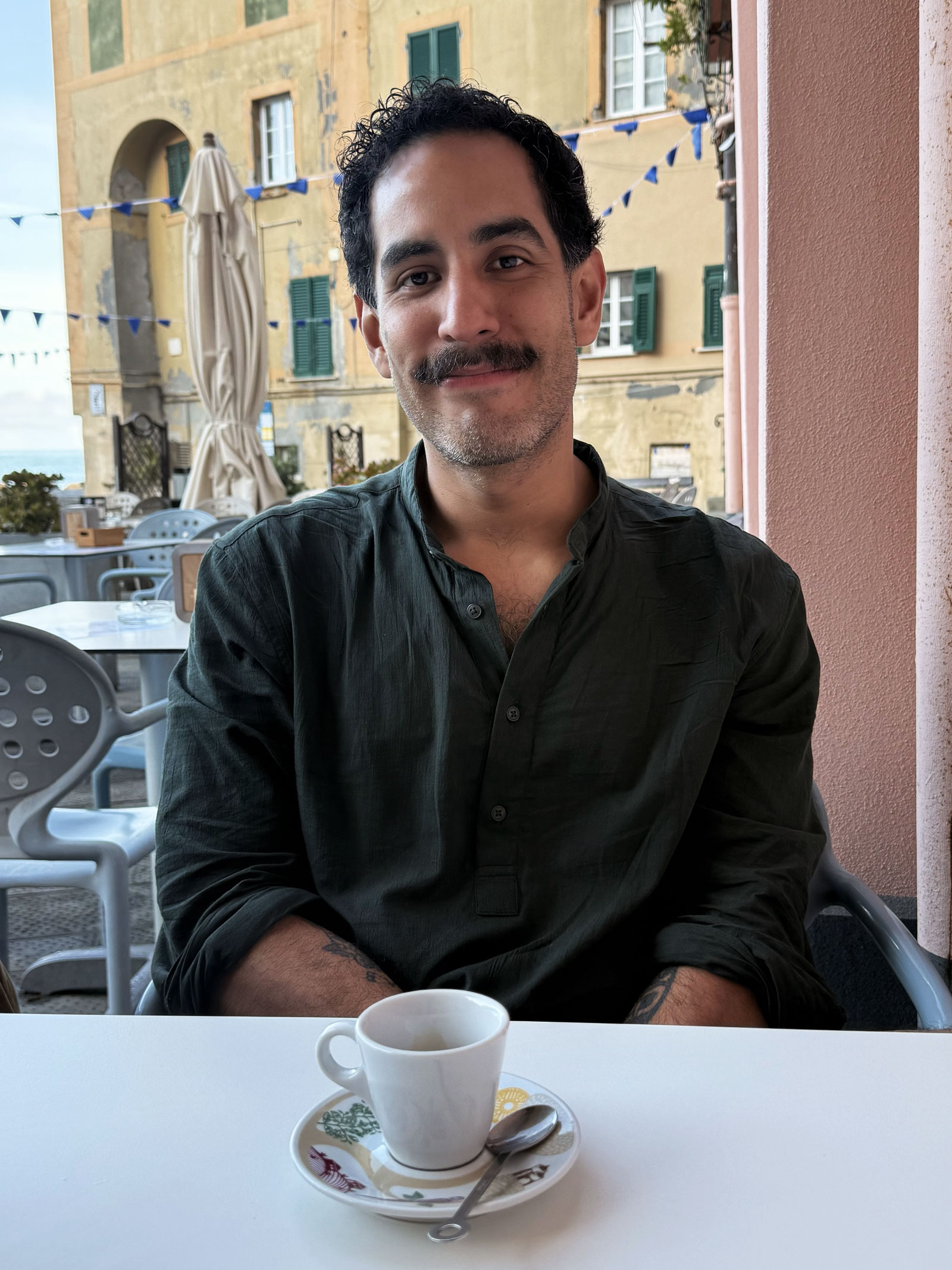 Giuseppe Orellana smiling over an espresso at a seaside café in Italy